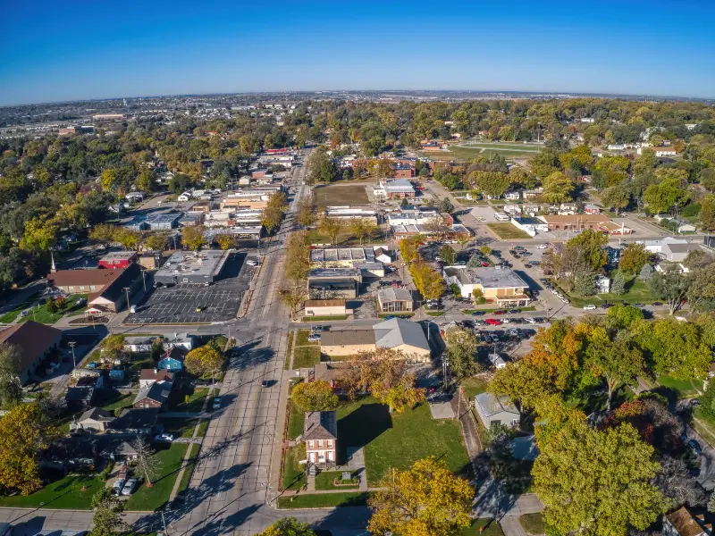 Aerial view of a small town with streets, buildings, and trees under a clear blue sky.