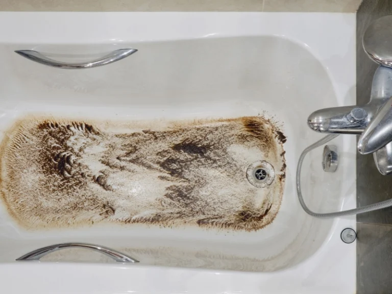 Bathtub with heavy brown dirt and grime stains around the drain and bottom surface.