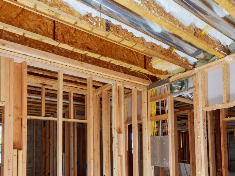 Exposed wooden framing and ceiling ducts inside a building under construction.