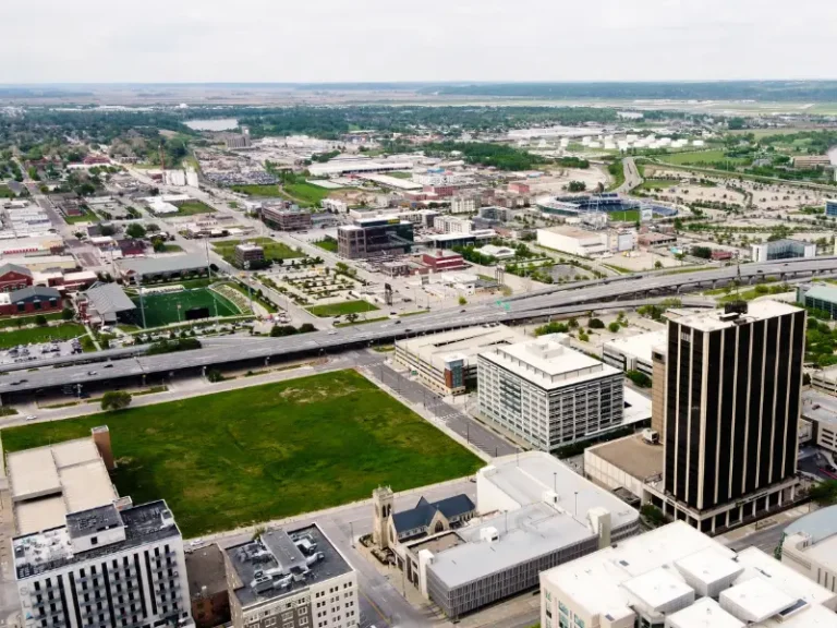 Aerial view of a cityscape with highways, office buildings, and a large green field.