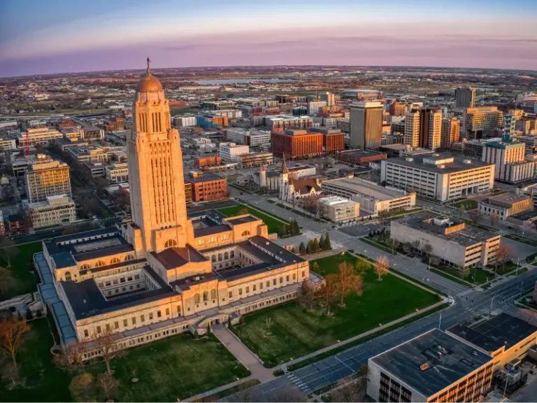 Aerial view of a large capitol building with a tall tower in a city at sunset.