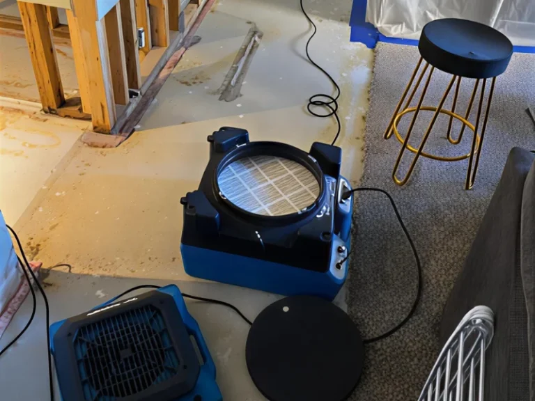 Two blue air scrubbers or air movers on a floor next to a black stool with gold legs.
